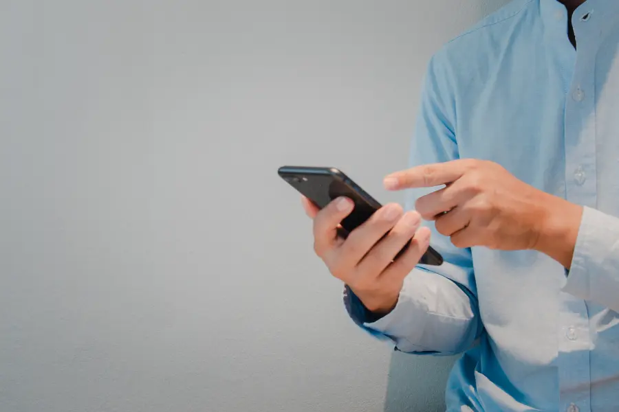 Person using a phone to submit an application online through iWorQ's Portal Home.